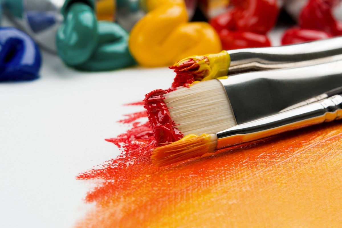 Pinceaux, peinture et couleurs sur une table de création.