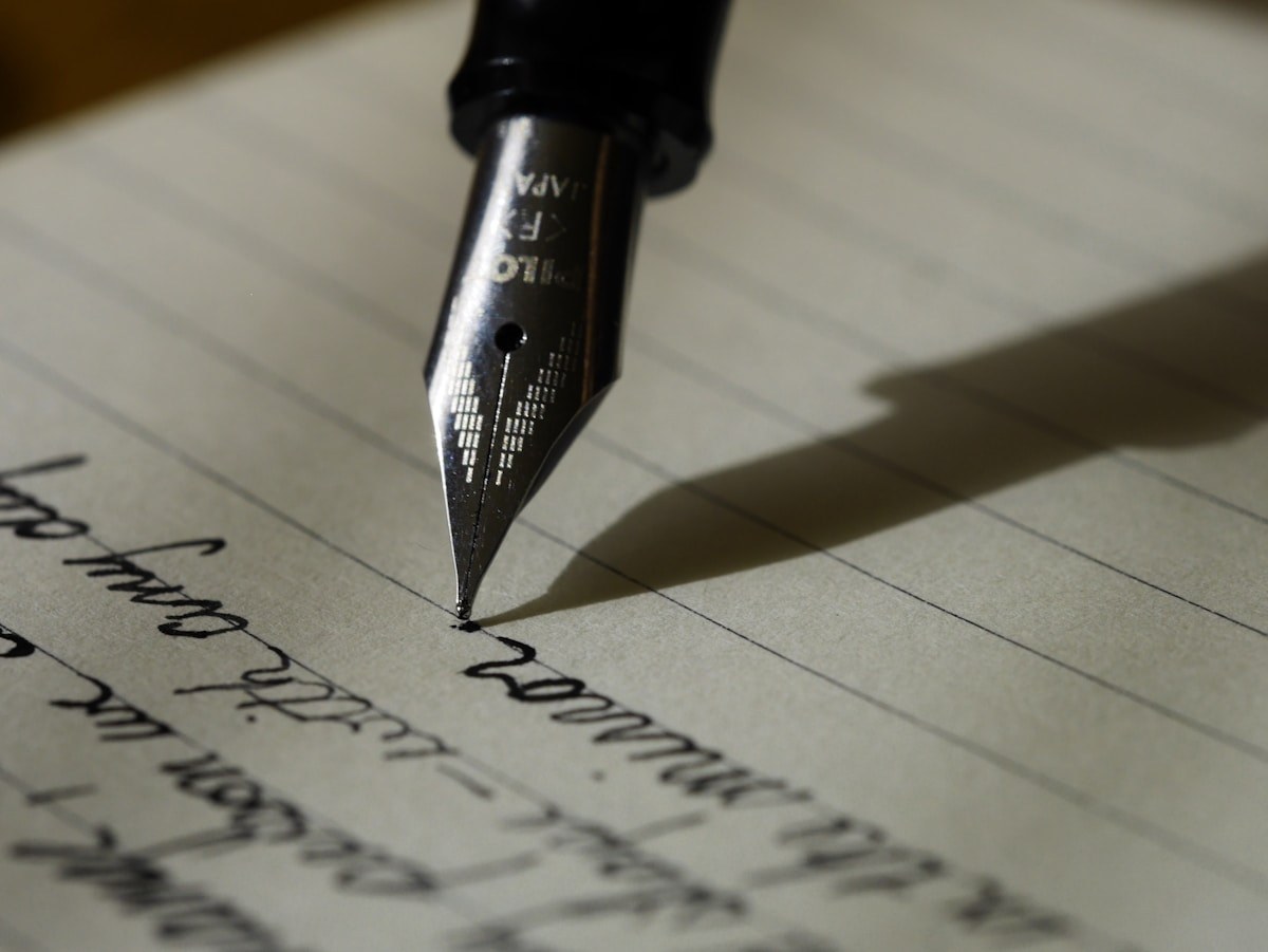 Une plume de stylo sur une page manuscrite.